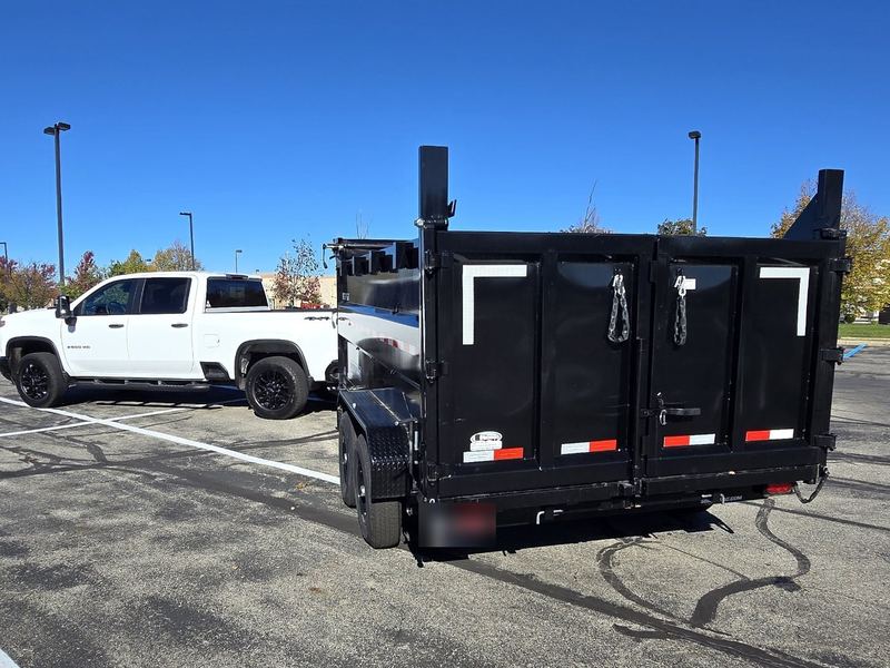 Arch City Property Care's white Chevrolet Silverado 2500HD and black dump trailer, seen from behind the trailer